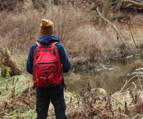 A person wearing a red backpack in the outdoors.