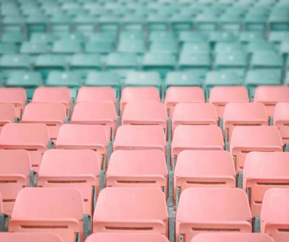 Rows of pink and blue chairs in a stadium.