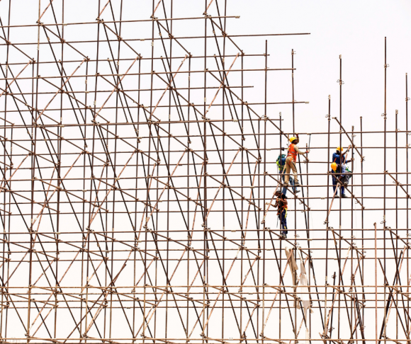 Construction workers working at height on scaffolds.