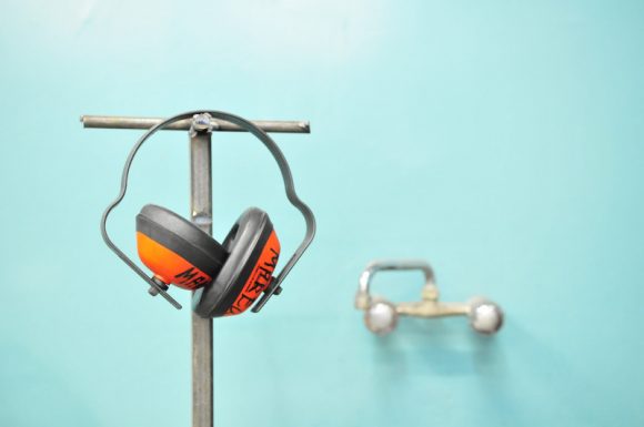 A pair of orange ear muffs hanging off a post.