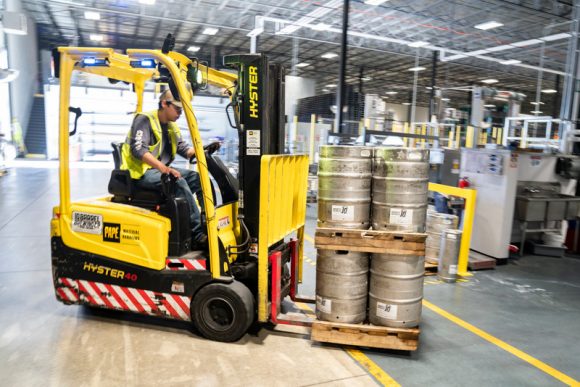 A worker driving a forklift with silver canisters on.