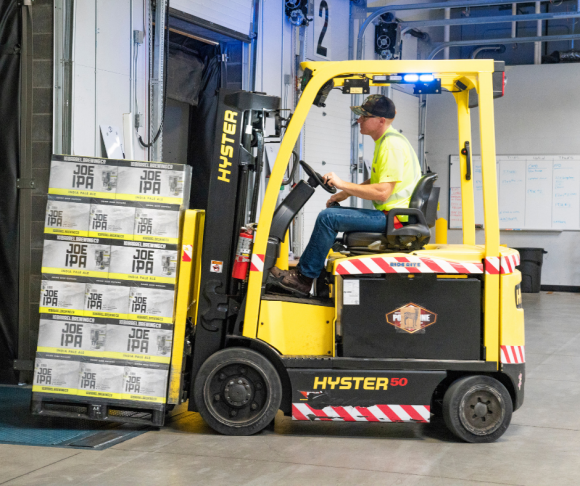 A worker driving a forklift with products on.