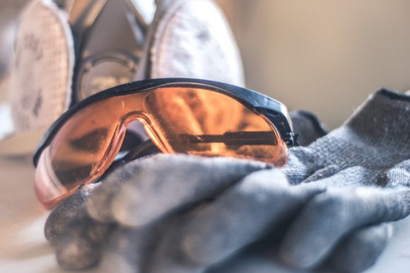 Safety glasses resting on top of a pair of grey work gloves.