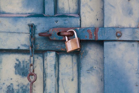 A rusted door locked with a padlock.