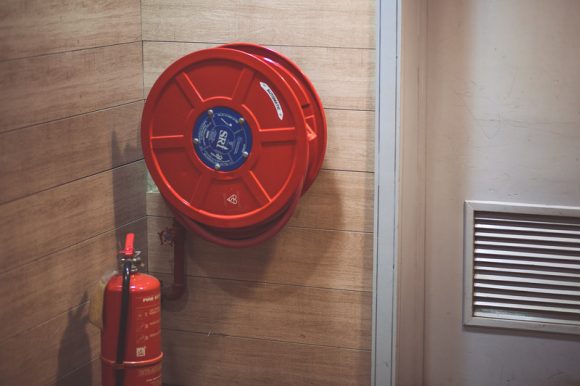 Red Fire Extinguisher Beside Hose Reel Inside a Room