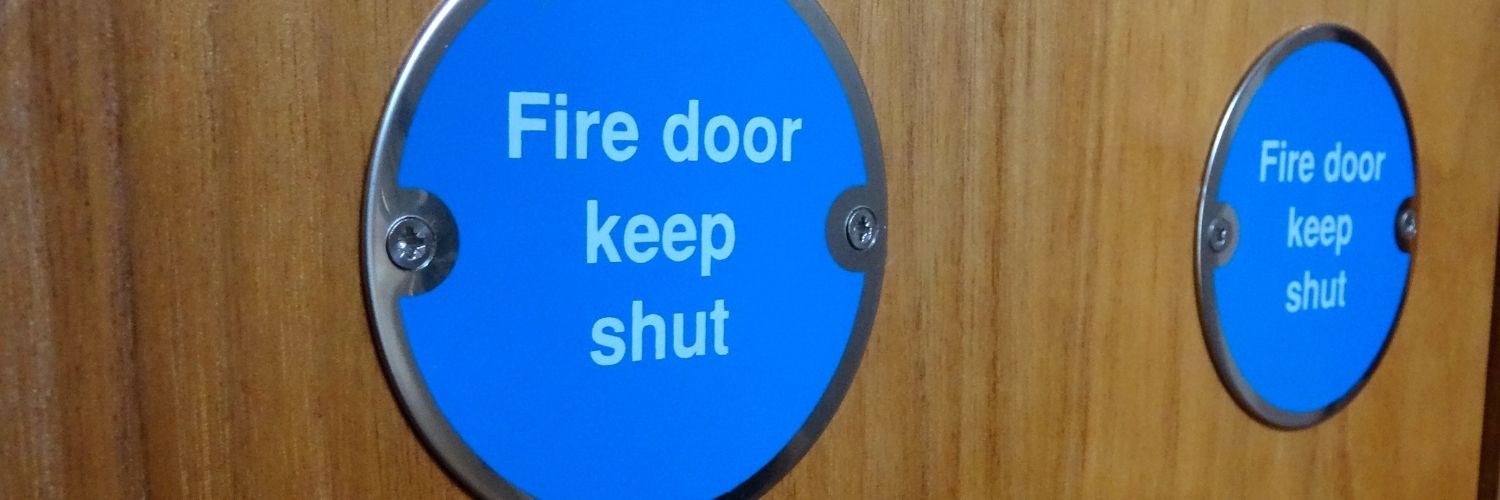 Close up of blue 'fire door keep shut' sign with white writing