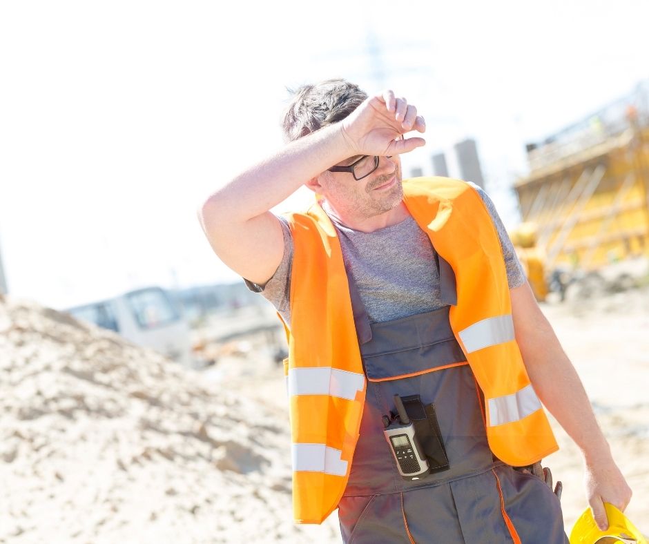 Tired construction worker wiping sweat from his brow on a sunny day