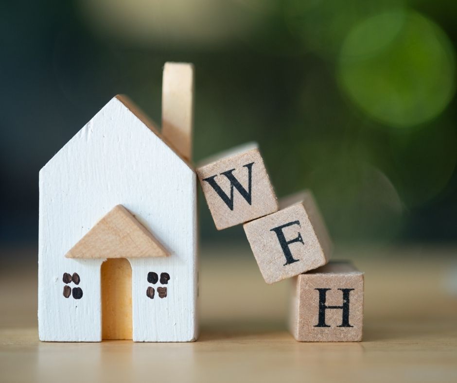 Miniature wooden house with stacked up wooden blocks spelling 'WFH'