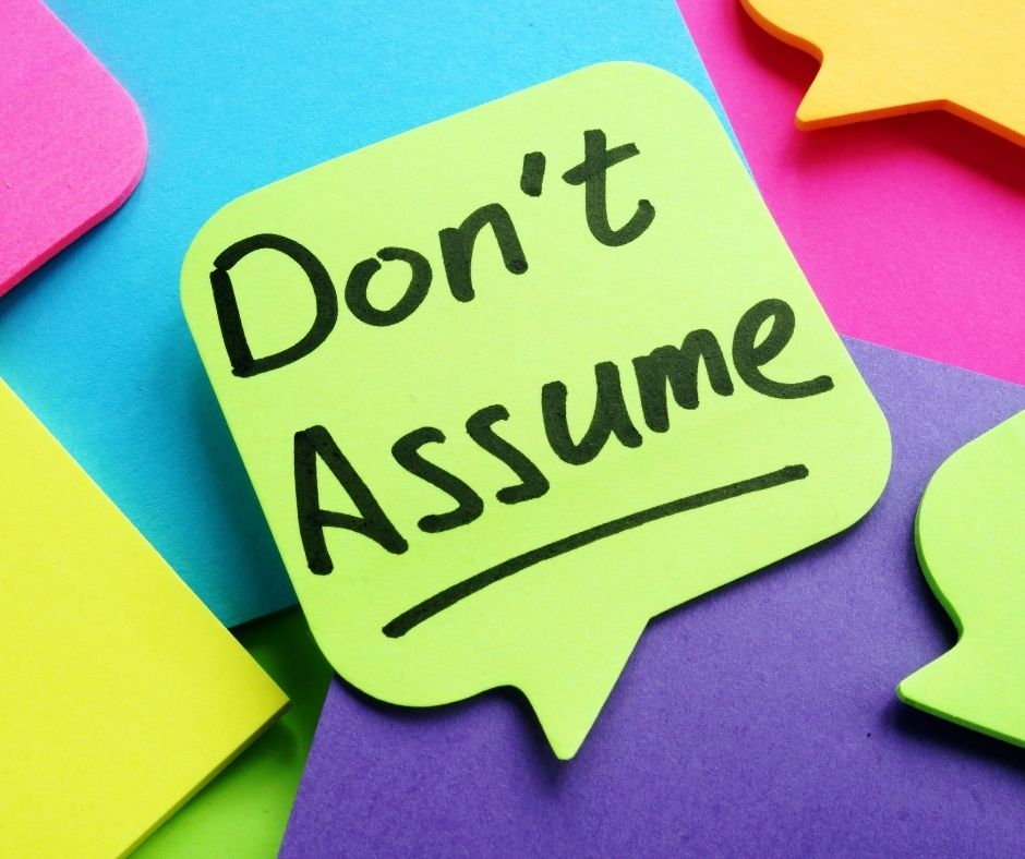 Speech bubble shaped post it note that says 'don't assume'