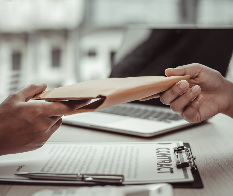 Person handing over a brown envelope over a contract