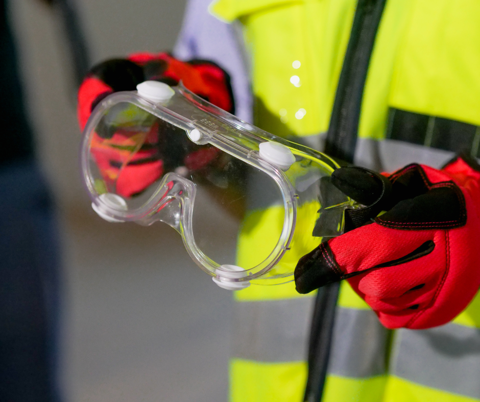 person wearing ppe (high vis jacket and gloves), holding eye protection glasses